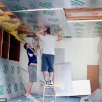 Un par de constructores instalan paneles de aislamiento térmico en las paredes y el techo de una casa antigua