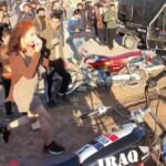 Imágenes impactantes muestran a una niña con un pañuelo en la cara mientras huye de una gran multitud de niños y hombres que la atacaron por vestirse 'poco modestamente' en un evento de motocicletas en Irak.