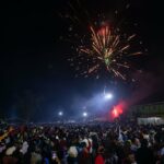 Fireworks light up the sky as people react while they celebrate after counting down to the new year at Miracle Center Cathedral in Kampala, Uganda, on January 1, 2023.
