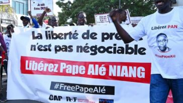 Senegalese journalists hold banners and shout slog