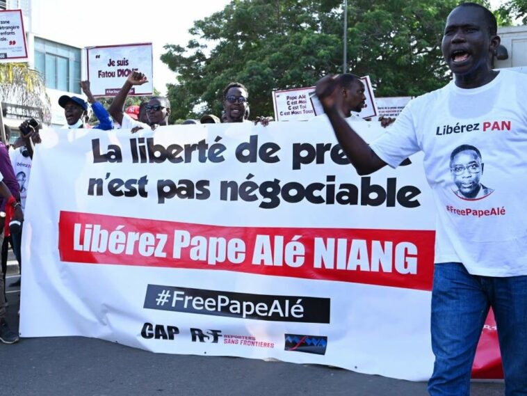 Senegalese journalists hold banners and shout slog
