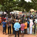 People gather under a tree to collect Permanent Voters Cards (PVC) from Officials of the Independent National Electoral Commission (INEC) at a ward in Lagos.
