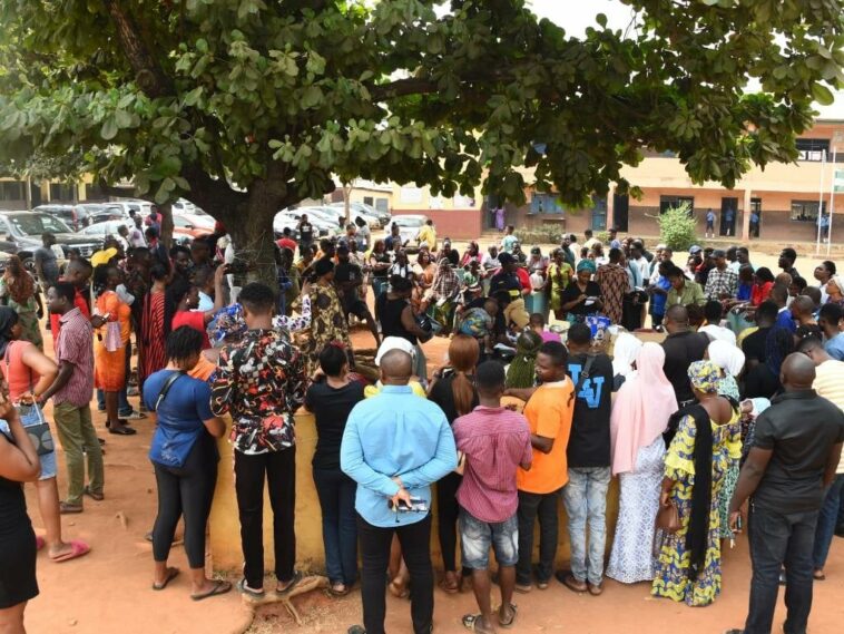 People gather under a tree to collect Permanent Voters Cards (PVC) from Officials of the Independent National Electoral Commission (INEC) at a ward in Lagos.