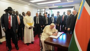 Pope Francis signing a book as President of South Sudan Salva Kiir, left, looks on at the Presidential Palace in Juba, South Sudan.