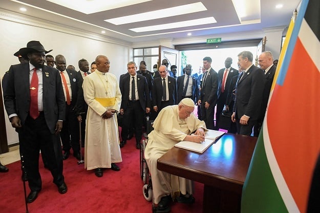 Pope Francis signing a book as President of South Sudan Salva Kiir, left, looks on at the Presidential Palace in Juba, South Sudan.