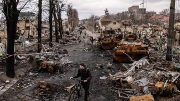 Un hombre empuja su bicicleta a través de los escombros y destruye vehículos militares rusos en la calle Vokzal'na el 6 de abril de 2022 en Bucha, cerca de Kiev.
