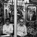 SUBWAY KISS (1987) - Los viajeros con gafas de sol viajan en un subterráneo sucio en Nueva York.  Se sientan con los brazos cruzados o las manos entrelazadas.  A través de una ventana rota, una pareja comparte un beso en la plataforma.  Sandler explicó: