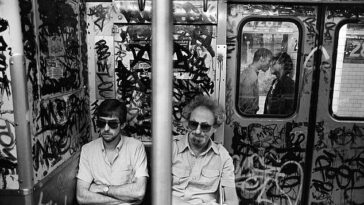 SUBWAY KISS (1987) - Los viajeros con gafas de sol viajan en un subterráneo sucio en Nueva York.  Se sientan con los brazos cruzados o las manos entrelazadas.  A través de una ventana rota, una pareja comparte un beso en la plataforma.  Sandler explicó: