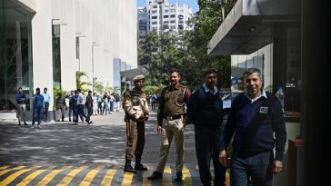 Oficiales de policía (centro) en la entrada del edificio que alberga las oficinas de la BBC que fueron allanadas por las autoridades fiscales indias en Nueva Delhi.