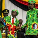 Zimbabwe's late president Robert Mugabe (L) holds his son (R) Robert Junior Mugabe's hand during a meeting of his party's youth league where he hinted at a cabinet reshuffle, on October 7, 2017, in Harare. JEKESAI NJIKIZANA / AFP