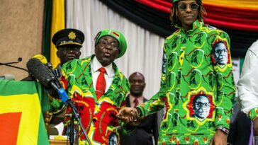 Zimbabwe's late president Robert Mugabe (L) holds his son (R) Robert Junior Mugabe's hand during a meeting of his party's youth league where he hinted at a cabinet reshuffle, on October 7, 2017, in Harare. JEKESAI NJIKIZANA / AFP