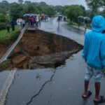 Chunk of collapsed road with onlookers observing