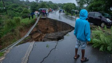 Chunk of collapsed road with onlookers observing