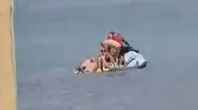 Hasta seis nadadores se amontonaron en una moto de agua salvavidas (arriba) después de que sonara una alarma de tiburón en Manly Beach