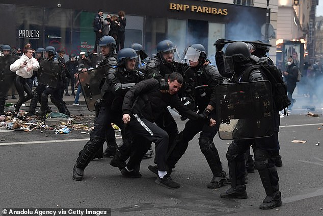 La mayor operación de seguridad en la historia reciente de Francia se desarrollará hoy para combatir a los alborotadores que quieren llevar 'fuego y sangre' a las calles, mientras continúan las protestas contra el aumento de las pensiones de Macron.  En la imagen: la policía antidisturbios detiene a un manifestante en París la semana pasada