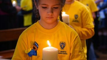 Los niños de la escuela ucraniana St Mary's encienden algunas de las 52 velas, una por cada semana de la guerra.