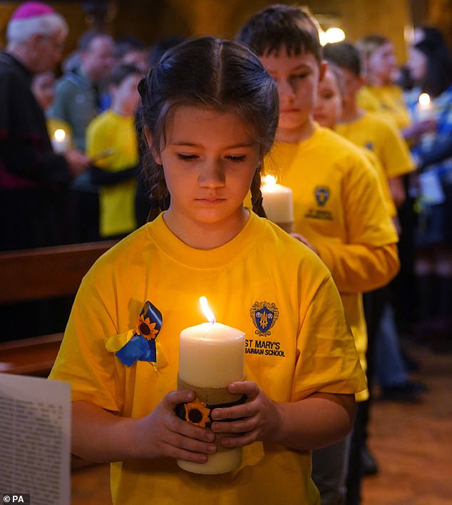 Los niños de la escuela ucraniana St Mary's encienden algunas de las 52 velas, una por cada semana de la guerra.