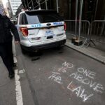 La policía mantiene una presencia predominante en la ciudad de Nueva York el miércoles mientras el país se prepara para una acusación contra el expresidente Donald Trump.  En la imagen: un oficial camina cerca de un grafiti de tiza que dice: