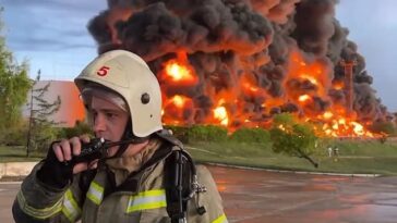 Una enorme bola de fuego se está librando en Crimea después de que un presunto ataque con drones aéreos ucranianos golpeó hoy un importante depósito de combustible en el corazón de un puerto naval anexado, Sebastopol (bombero en la foto)