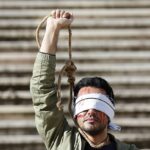 Un manifestante de la comunidad portuguesa iraní protesta frente al edificio del Parlamento en Portugal tras la sentencia de muerte y ejecución pública por parte de Irán de dos jóvenes manifestantes, Mohsen Shekari y Majidreza Rahnavard.
