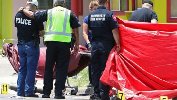 Un oficial de policía se consuela cuando las autoridades atendieron a los fallecidos en la parada de autobús afuera del Centro Ozanam en Brownsville, Texas, el domingo.
