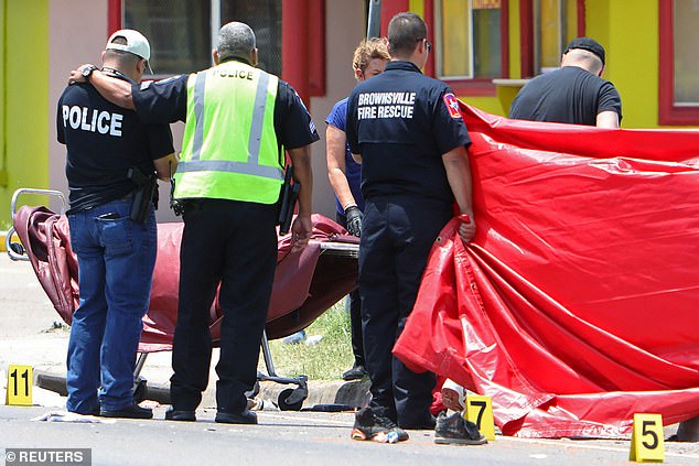 Un oficial de policía se consuela cuando las autoridades atendieron a los fallecidos en la parada de autobús afuera del Centro Ozanam en Brownsville, Texas, el domingo.