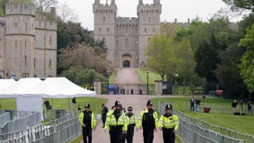Oficiales de policía recorren el Long Walk en Windsor, donde se llevan a cabo frenéticos preparativos de última hora para el Concierto de Coronación de esta noche.