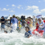 La gente juega en una playa en la ciudad de Shirahama, en la prefectura de Wakayama, en el oeste de Japón, el 3 de mayo de 2023. La popular playa para nadar, conocida por su arena blanca, abre el mismo día, la primera entre las playas de la isla principal japonesa de Honshu. .  (Kiodo)