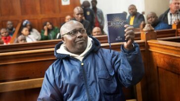 Fulgence Kayishema holds up a Christian book as he sits in the Cape Town Magistrate's Court.