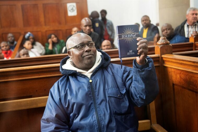 Fulgence Kayishema holds up a Christian book as he sits in the Cape Town Magistrate's Court.