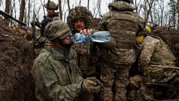 Un militar ucraniano le da agua a un soldado ruso capturado cerca de Bakhmut el jueves.