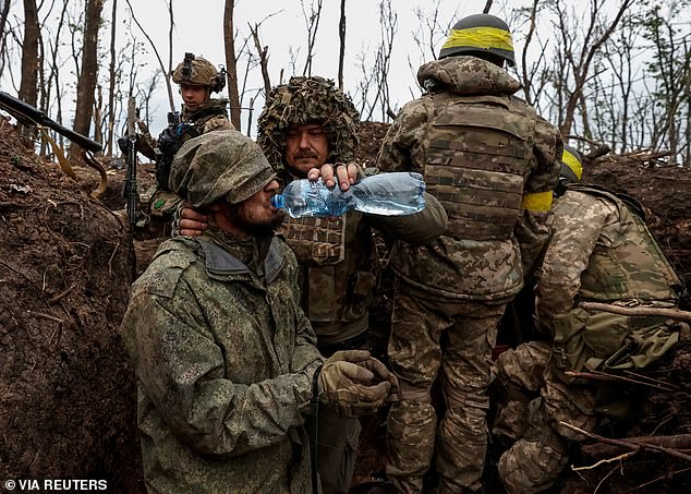 Un militar ucraniano le da agua a un soldado ruso capturado cerca de Bakhmut el jueves.