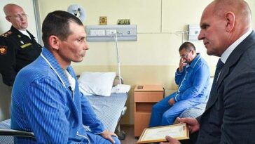 El Ministerio de Defensa de Rusia publicó un video que muestra a Andrei Kravtsov (izquierda), sentado en una cama de hospital y recibiendo un certificado de recompensa de Alexander Karelin (derecha).