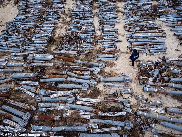 Esta fotografía aérea tomada el 7 de diciembre de 2022 muestra a un experto de la oficina del fiscal examinando los restos recolectados de proyectiles y misiles utilizados por el ejército ruso para atacar la segunda ciudad más grande de Ucrania, Kharkiv.