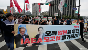 Los manifestantes marchan hacia la embajada japonesa durante una manifestación contra la decisión del gobierno japonés de liberar agua radiactiva tratada de la planta de energía nuclear dañada de Fukushima, en Seúl, Corea del Sur, el 8 de julio de 2023. Las cartas dicen: "Descartar el informe de la OIEA." (AP)