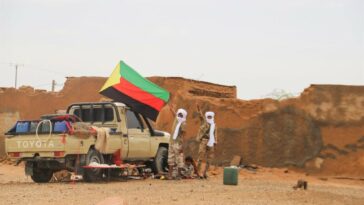 Fighters for The National Movement for the Liberation of Azawad (MNLA) hold up their flag in Kidal in August 2022. (Photo by SOULEYMANE AG ANARA / AFP)
