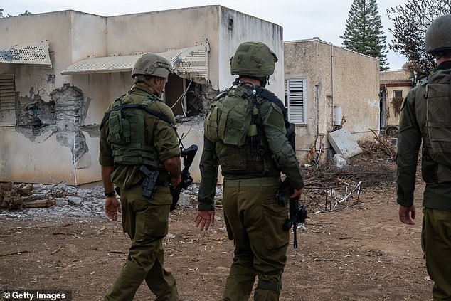 Soldados de las FDI pasan junto a casas que fueron destruidas el 7 de octubre cuando Hamás atacó este kibutz cerca de la frontera con Gaza el 12 de noviembre de 2023 en Kfar Aza.