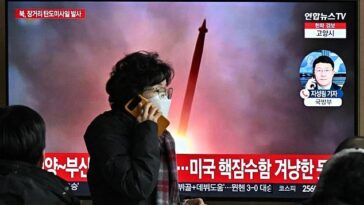 Después de que Corea del Norte probara otro misil de largo alcance, una mujer en Seúl pasa junto a una pantalla de televisión que muestra un noticiero con imágenes de archivo de una prueba de misil anterior.