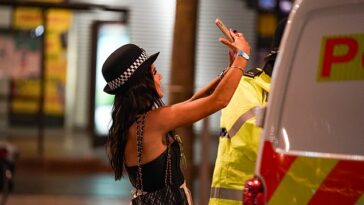 Una niña en Nottingham con casco de policía se hace un selfie junto a una furgoneta policial y un agente