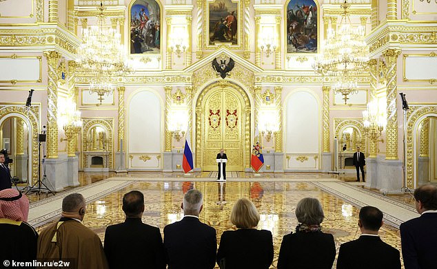 Se podía ver a Putin hablando con confianza mientras se encontraba a una distancia incómoda de los embajadores frente a una enorme puerta dorada con banderas a cada lado.