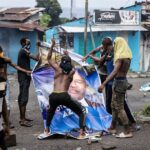 Opposition supporters destroy a billboard featuring re-elected President Azali Assoumani, during a demonstration in Moroni on 17 January  2024. (Photo by OLYMPIA DE MAISMONT / AFP)