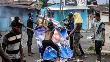 Opposition supporters destroy a billboard featuring re-elected President Azali Assoumani, during a demonstration in Moroni on 17 January  2024. (Photo by OLYMPIA DE MAISMONT / AFP)