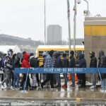 Un grupo de migrantes recibe alimentos fuera de la zona de aterrizaje de migrantes durante una tormenta invernal el 12 de enero de 2024 en Chicago, Illinois.