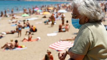 FOTO DE ARCHIVO: Una mujer con mascarilla observa a la gente tomando el sol en la playa de Las Canteras en Las Palmas de Gran Canaria, la isla de Gran Canaria, España, el 31 de mayo de 2020.