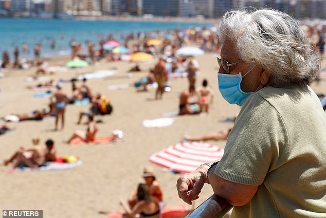 FOTO DE ARCHIVO: Una mujer con mascarilla observa a la gente tomando el sol en la playa de Las Canteras en Las Palmas de Gran Canaria, la isla de Gran Canaria, España, el 31 de mayo de 2020.