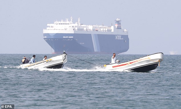 Los barcos pasan junto al carguero Galaxy Leader, incautado por los hutíes frente a la costa del puerto de Al-Salif en el Mar Rojo, en la provincia de Hodeidah, Yemen.