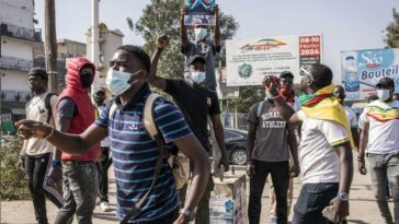 Protestors hold stones and portraits of Senegalese opposition leader Ousmane Sonko during clashes with police in Dakar on February 9, 2024.