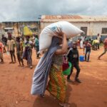 A woman carries a bag of food distributed by the World Food Program (WFP) to displaced people from the province of Cabo Delgado, at the 21 de Abril Tribune School in the town of Namapa, Erati district of Nampula, Mozambique. (Alfredo Zuniga/ AFP)