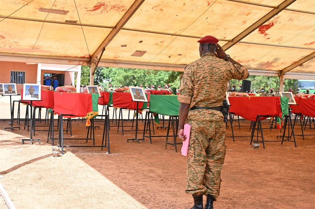 A soldier salutes in front of the coffins of 27 soldiers killed in an ambush claimed by Al-Qaeda in 2022. Human Rights Watch alleges that, in revenge for jihadist attacks on the military, soldiers executed hundreds of villagers. (Issouf SANOGO / AFP)