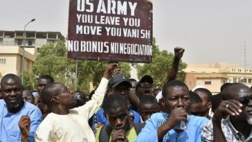 Protesters react as a man holds up a sign demanding that soldiers from the United States Army leave Niger without negotiation during a demonstration in Niamey, on April 13, 2024. The United States agreed on April 19 to withdraw its more than 1,000 troops from Niger, officials said, upending its posture in West Africa where the country was home to a major drone base. (Photo by AFP)